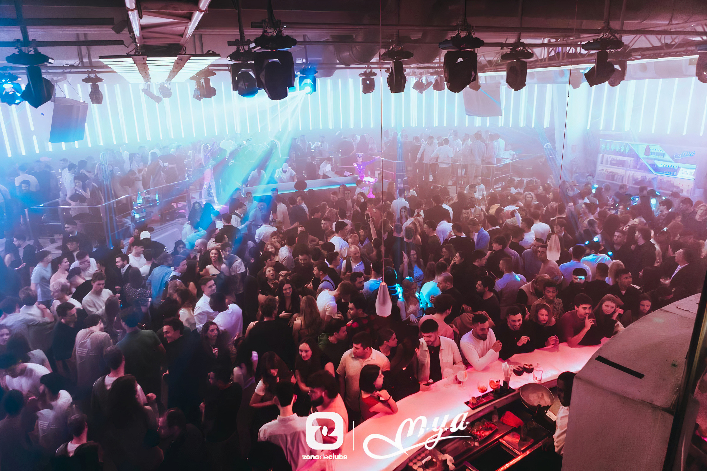 Crowd dancing under colorful lights during a packed night at MYA Club in Valencia.